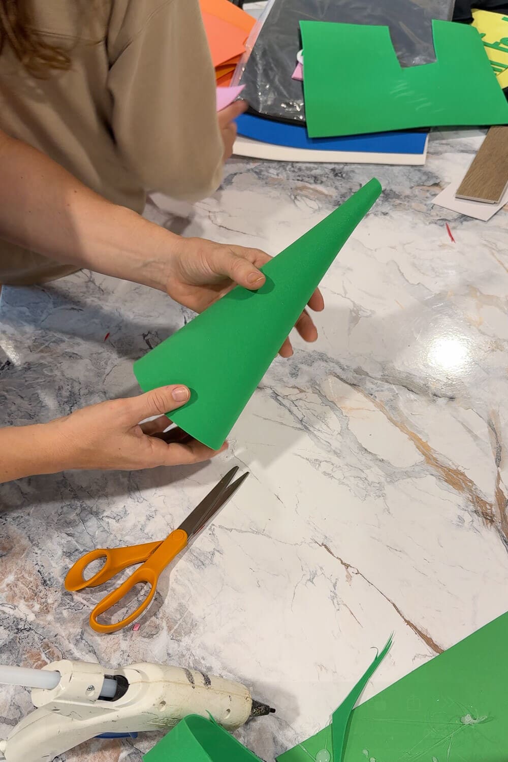 Holding a finished green foam cone to form a pointed gnome hat for a DIY kids garden gnome costume.
