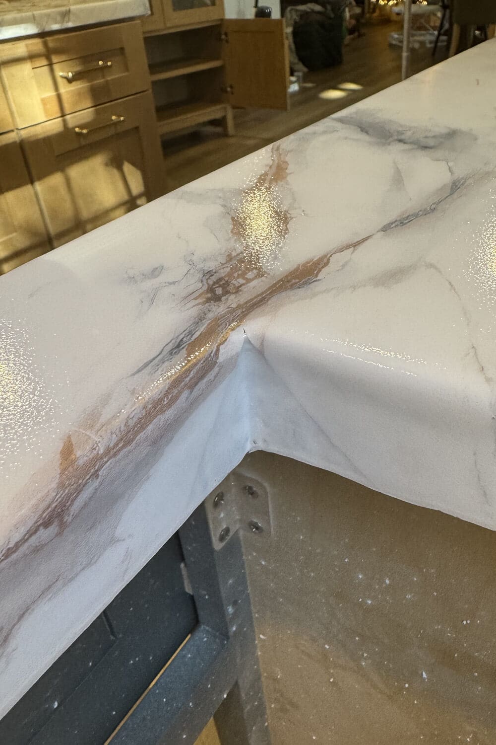 Close-up of DIY faux marble countertop corner with marble contact paper wrapped and freshly coated in epoxy, showing a glossy finish and how the seams meet on an outside edge.