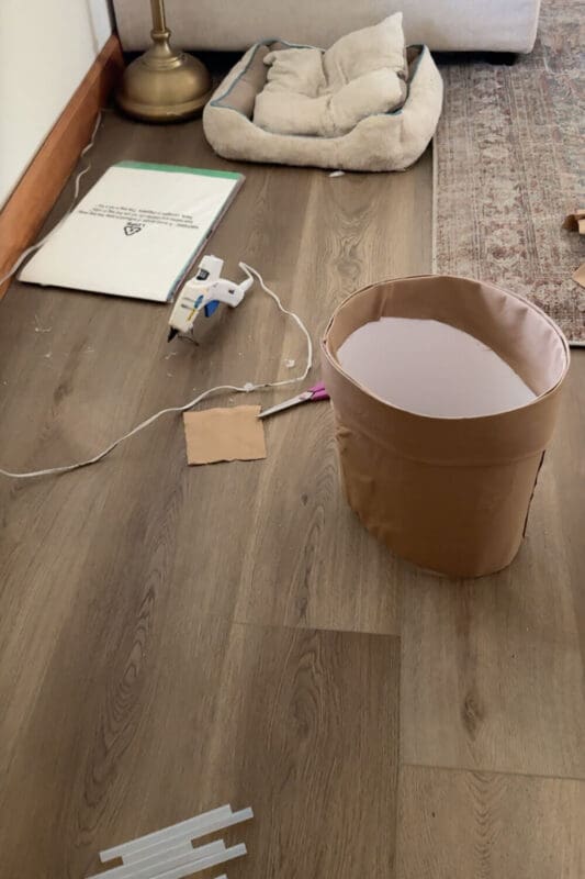 Finished terracotta-pot skirt wrapped in brown fabric, hot glue gun and scissors nearby, part of a kids DIY Halloween dress up.