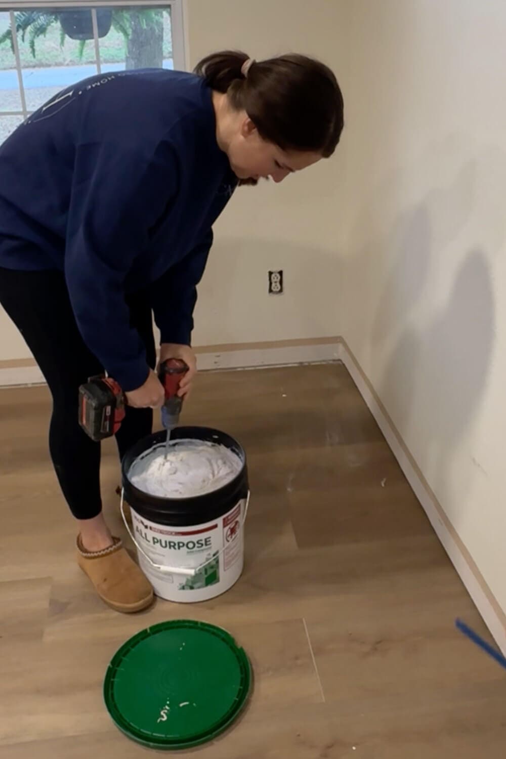 Mixing premixed joint compound with a drill and paddle mixer to get a smooth consistency before skim coating the wall