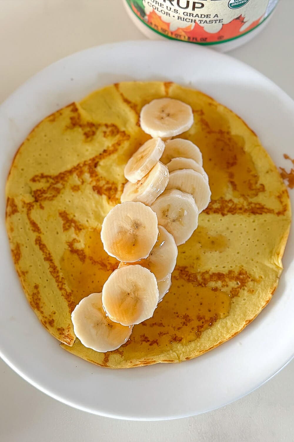 No-carb cottage cheese egg banana with banana slices and maple syrup on a white plate.