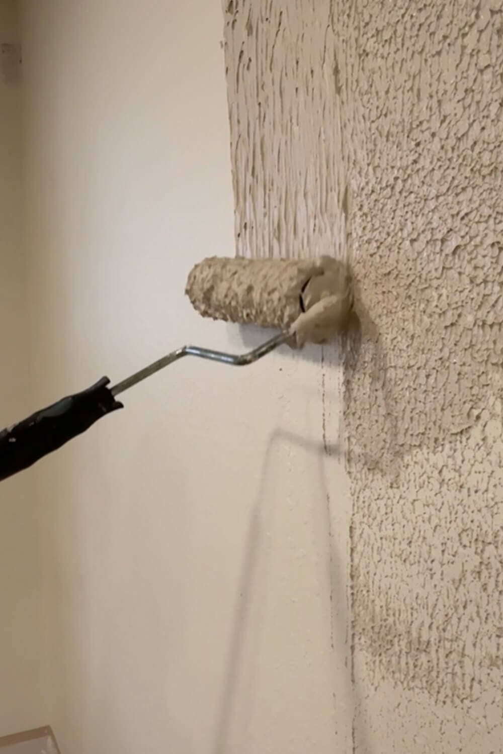 Rolling joint compound onto a textured wall to start skim coating and fill in the heavy texture before smoothing it flat