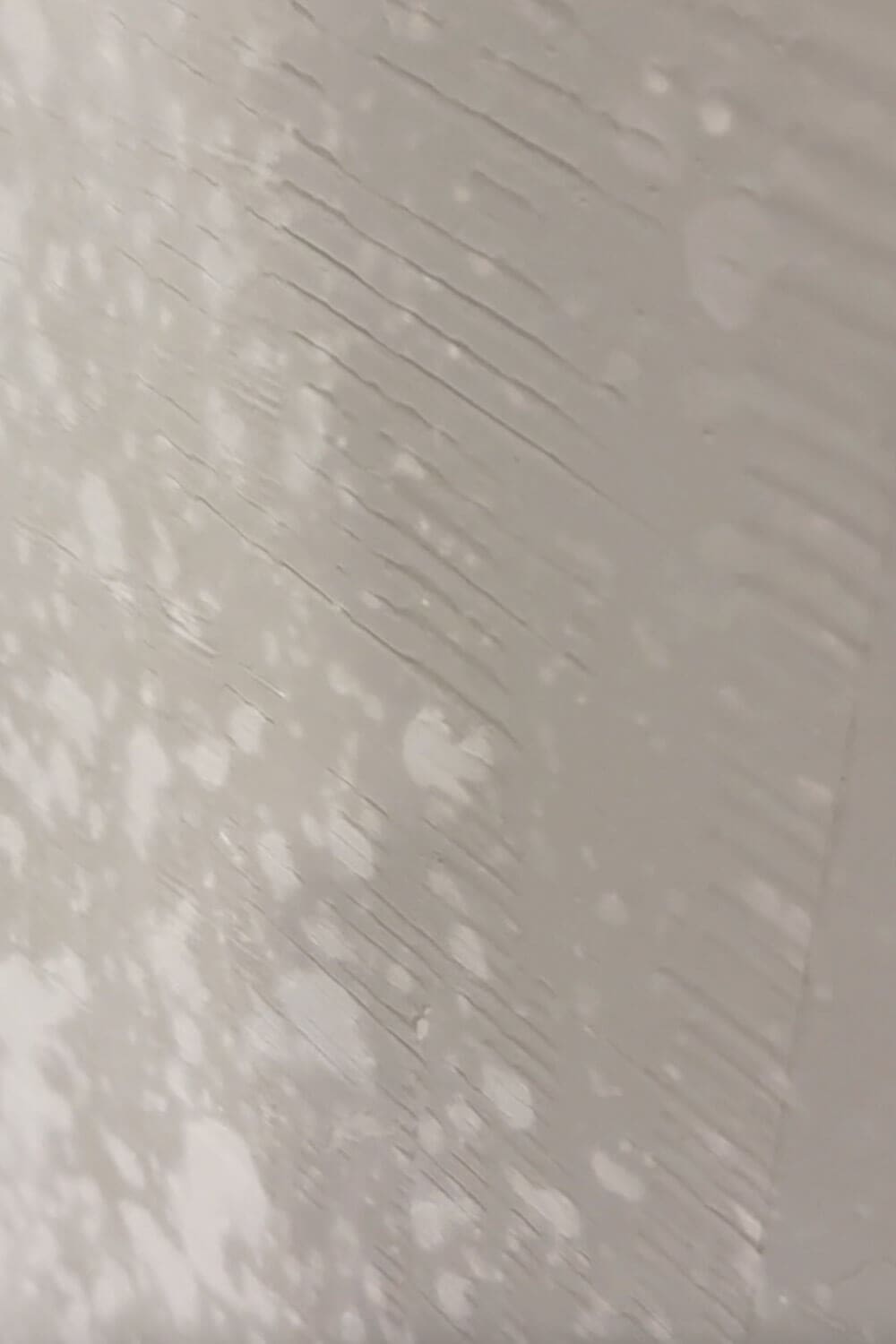 Close-up of skim coating a wall with joint compound, showing trowel marks, ridges, and skipped spots that need smoothing