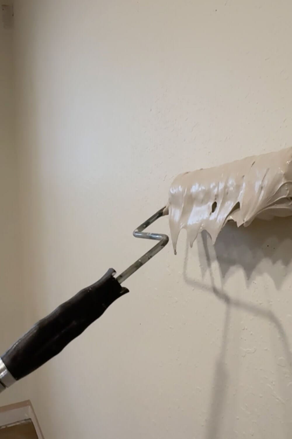 Close-up of a paint roller loaded with joint compound for skim coating a wall and covering texture before trowel smoothing