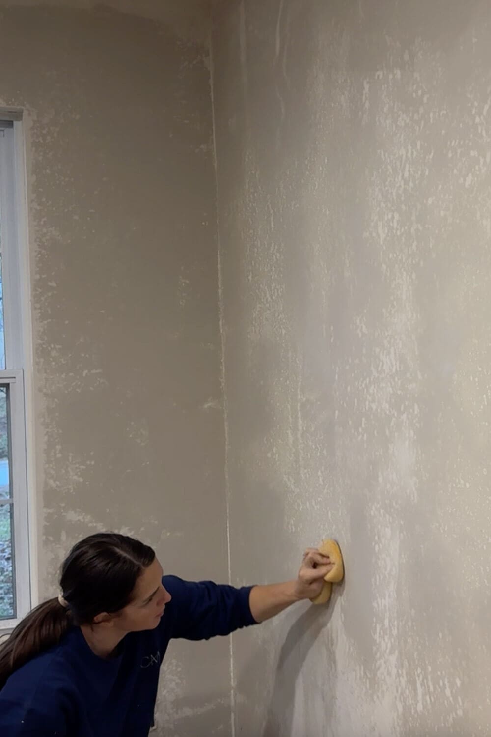 Wet sponging a skim coated wall to smooth out joint compound and blend out trowel lines for an even finish