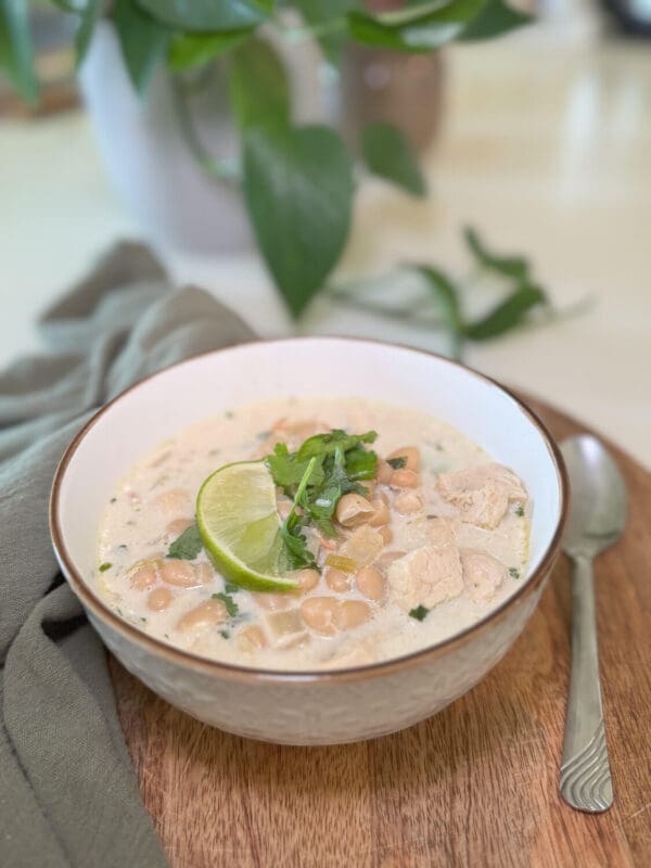 Creamy white chicken chili in a ceramic bowl, packed with white beans and tender chicken, topped with a lime wedge and cilantro—cozy weeknight soup.
