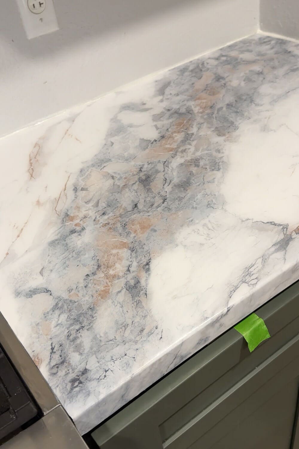 DIY countertops that look like marble in a small kitchen, showing the marble contact paper pattern sealed with epoxy above green cabinets.