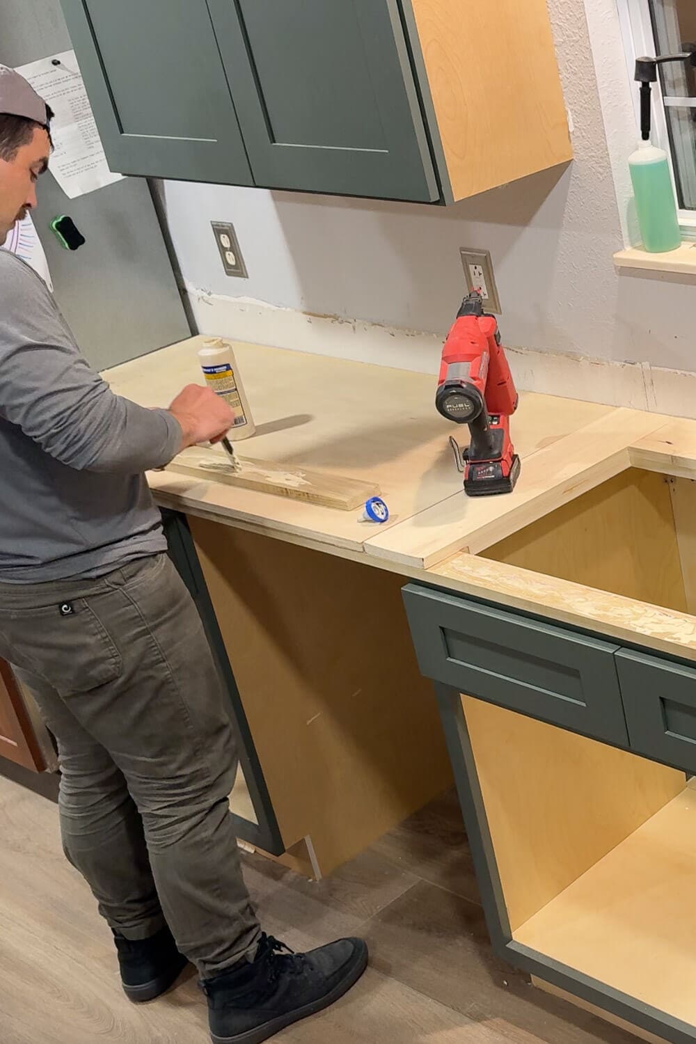 Spreading wood glue on a trim board while building plywood counters, prepping the area for a kitchen sink.