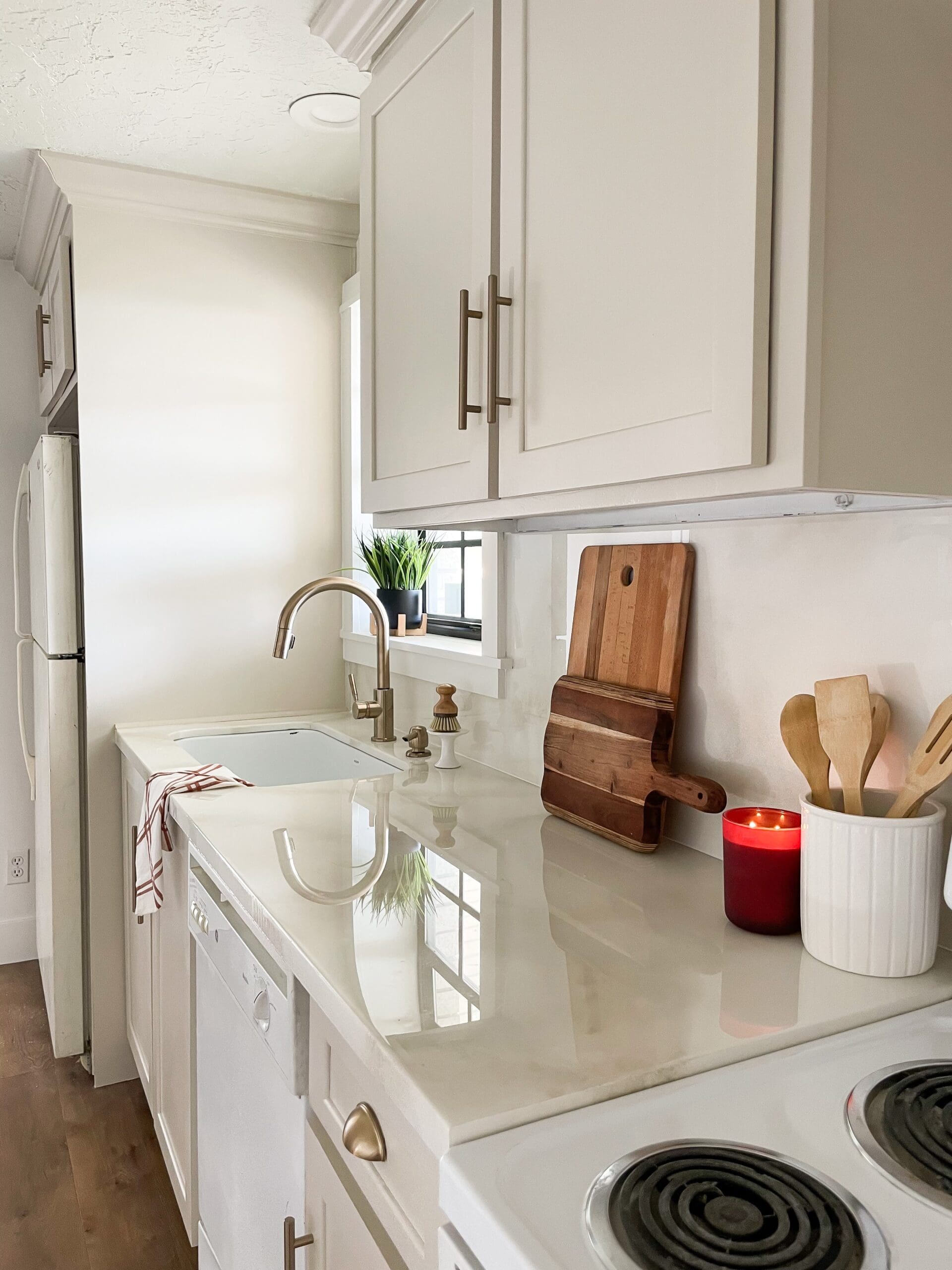 Bright white kitchen with DIY epoxy countertops, white cabinets, brass hardware, and styled decor, showing how epoxy countertops can look like real marble in a small galley kitchen.