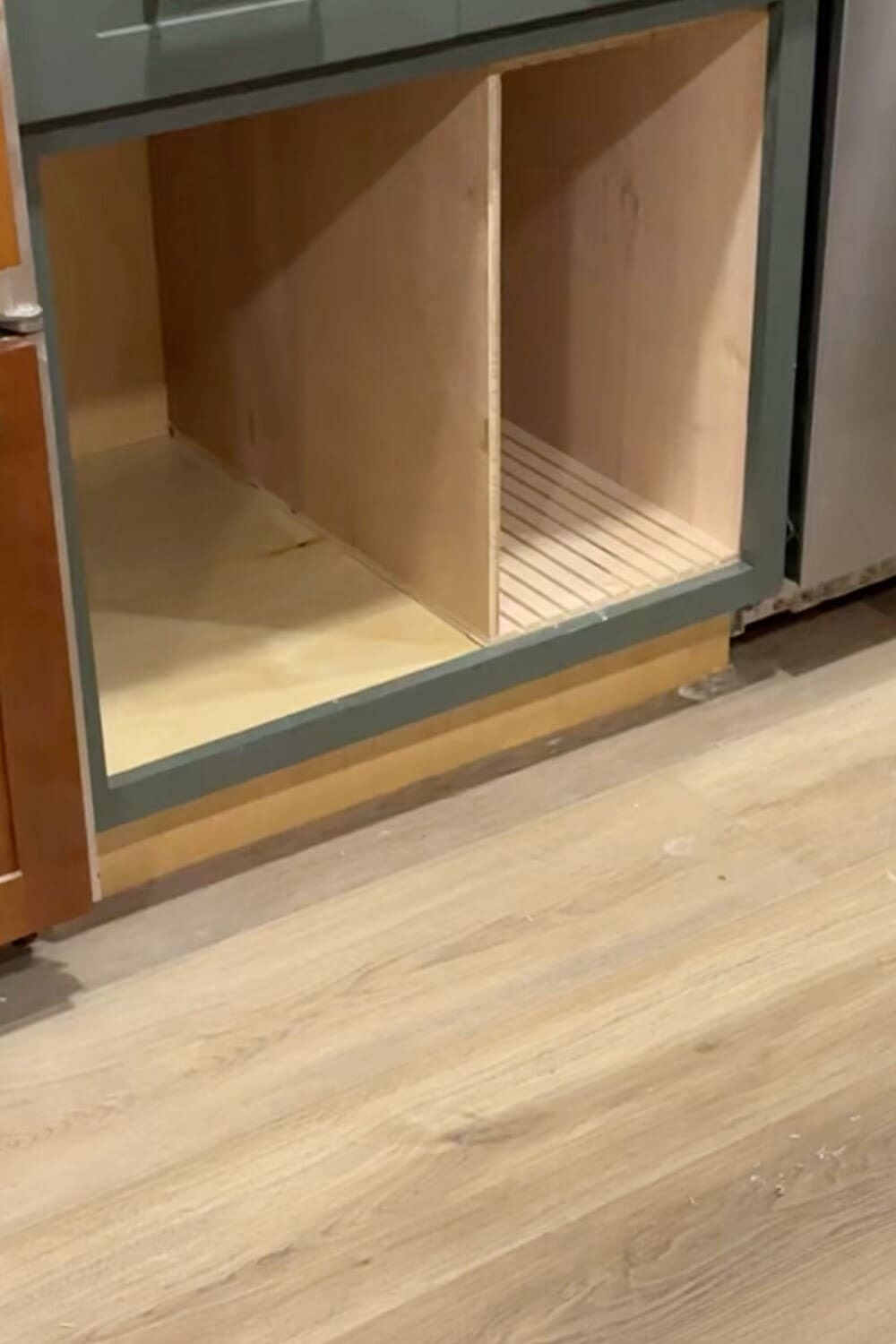 Lower kitchen cabinet with a custom plywood sheet pan organizer box installed on one side and open space on the other