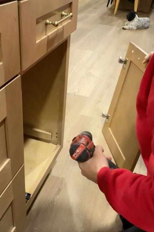 Removing the original door to place an insert for the garbage bin.