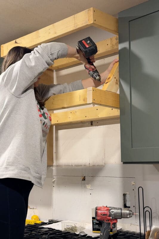 Attaching an angled 2x4 support brace to connect the top and bottom of the DIY range hood cover frame.