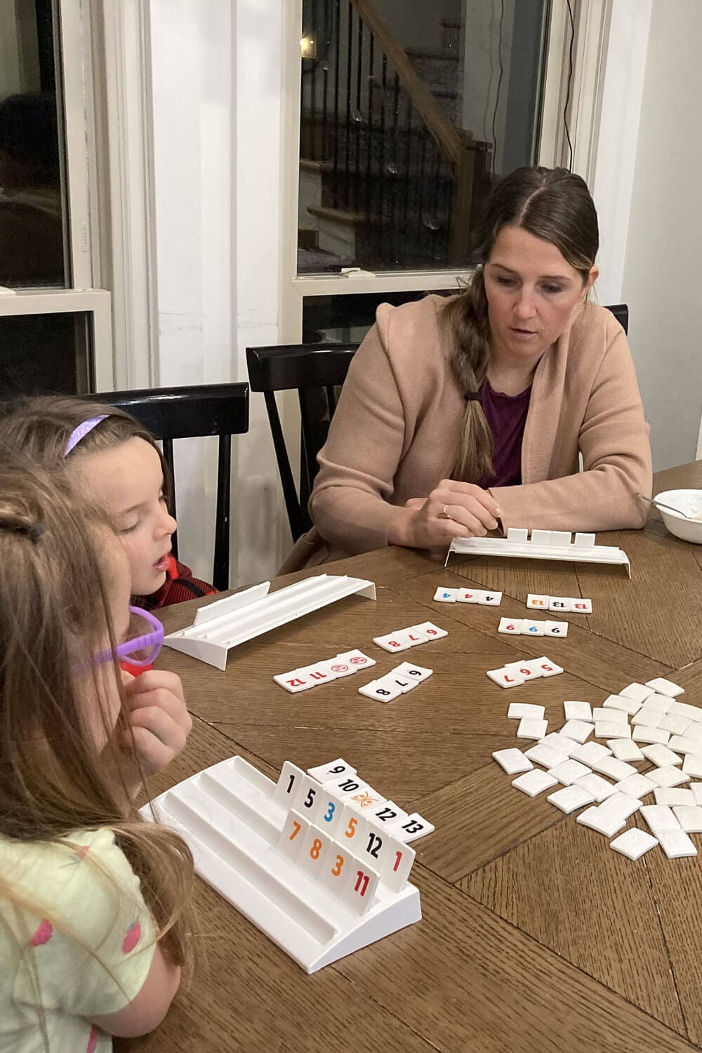 Board Game Storage Ideas showing family game night playing Rummikub at the dining table, with tile racks and numbered tiles laid out for an easy, grab-and-play board game setup.