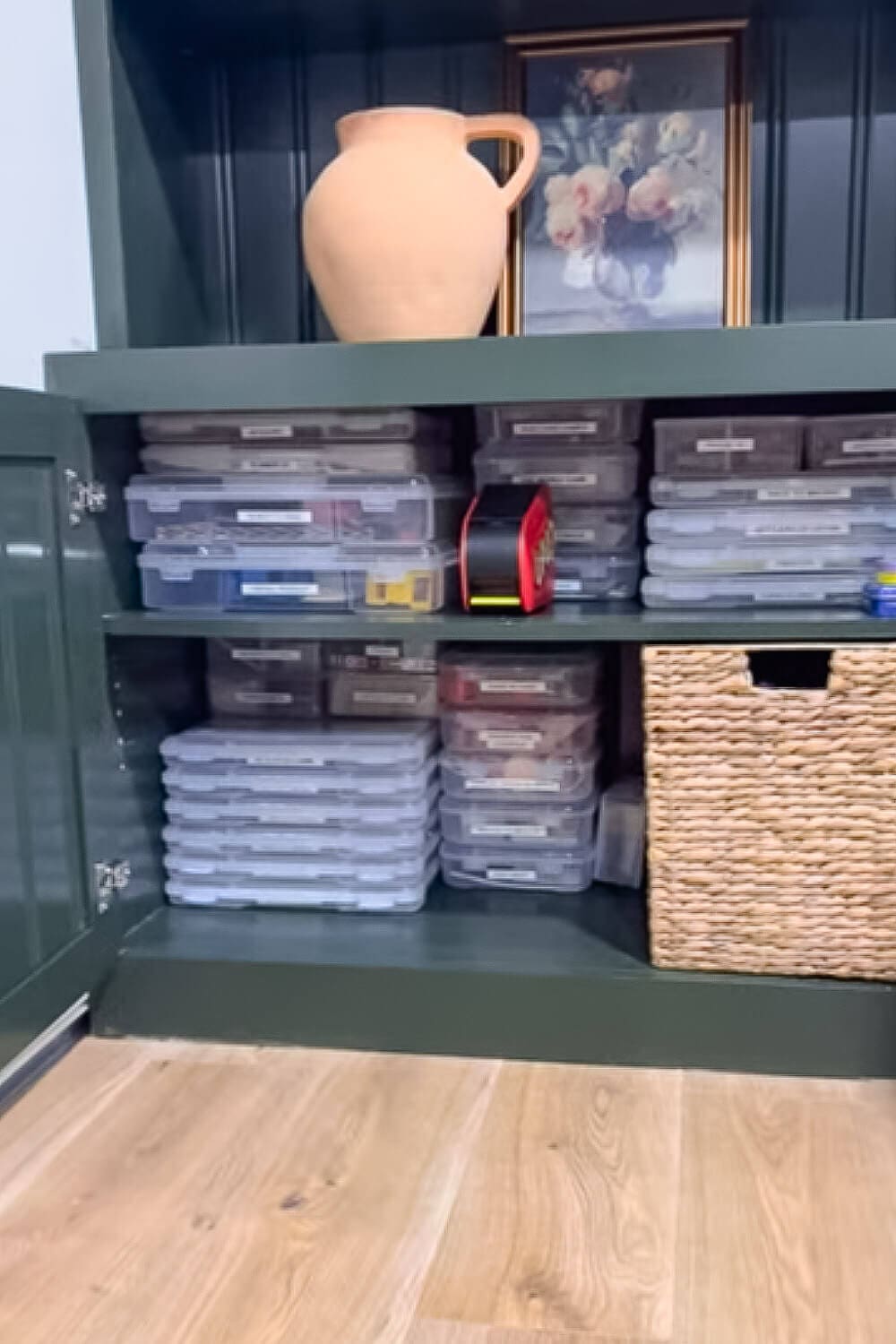 Board Game Storage Ideas showing a game cabinet organized with uniform, labeled plastic cases stacked neatly on shelves, plus a woven basket bin for extra game pieces and accessories.