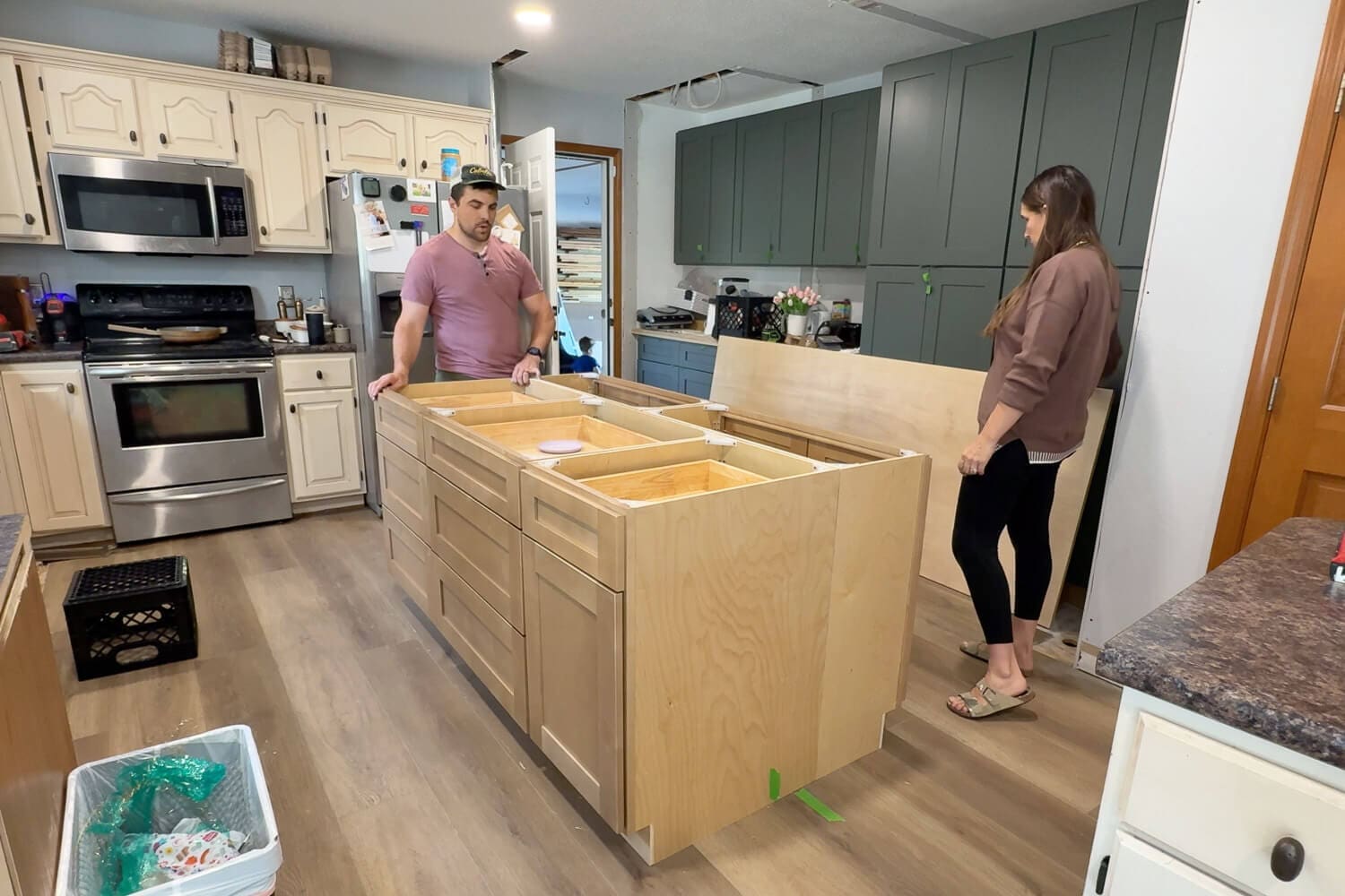 Laying out and assembling cabinet boxes to create a custom kitchen island during our DIY kitchen renovation, with the old kitchen still in the background.