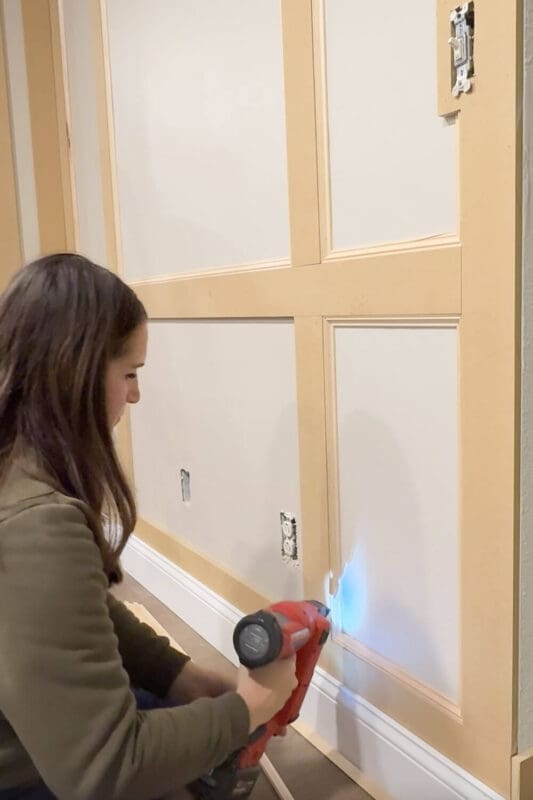 Installing the inner trim piece on a tall box molding panel to create crisp picture frame details during a DIY wall trim project.