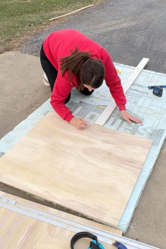 Tracing an arch on a plywood panel with a string to create a curved detail.