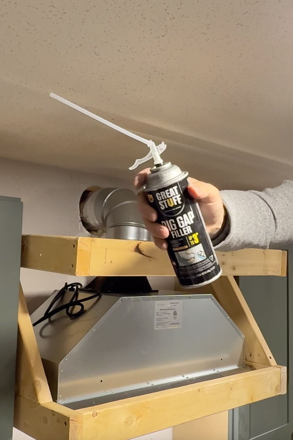 Using expanding foam around the range hood vent duct to seal gaps and keep out air, bugs, and rodents.