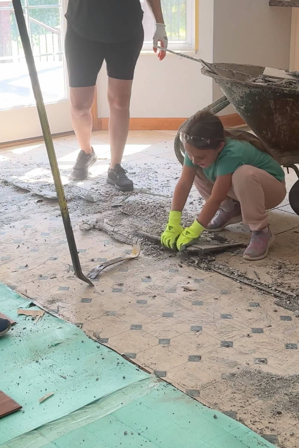One of my kids helps with demo by pulling up pieces of the old tile flooring and adhesive while we load debris into a wheelbarrow.