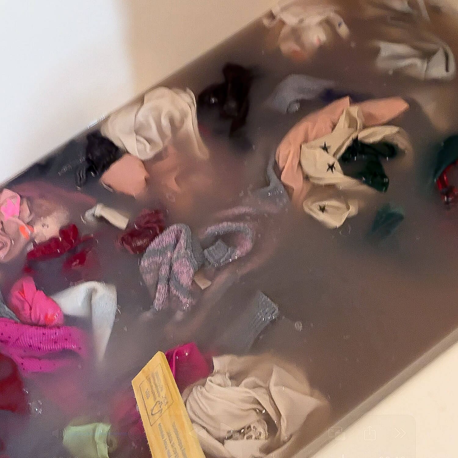 Close-up of laundry stripping in a bathtub with murky water and mixed clothes soaking as the deep clean pulls out gross buildup and trapped odors.