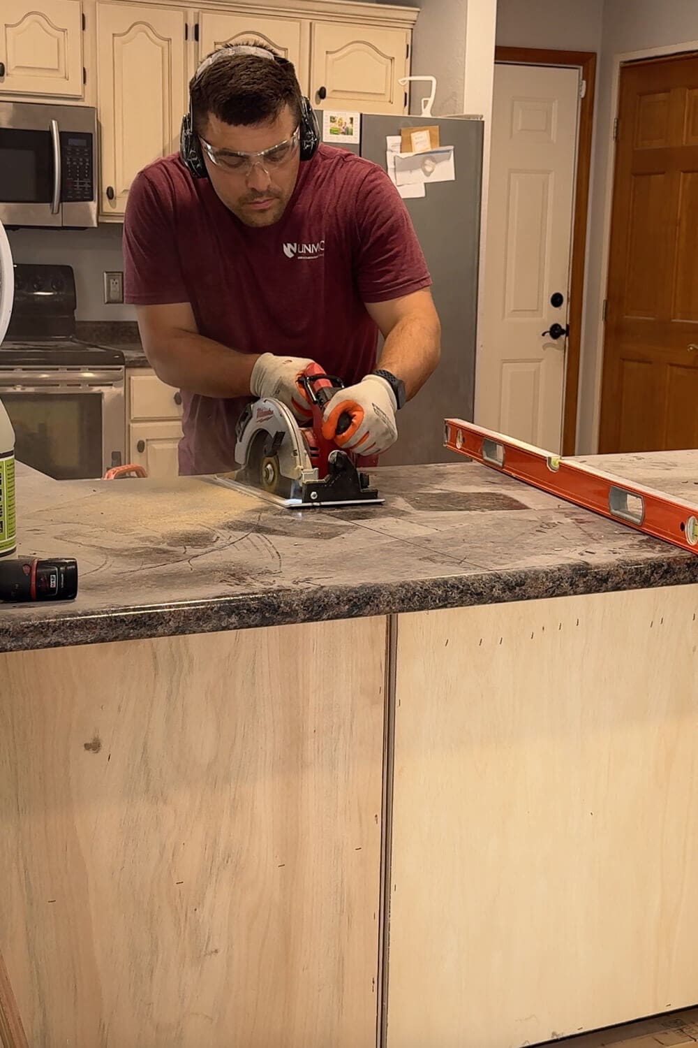 Wearing safety glasses and ear protection, we use a circular saw to cut through the old kitchen peninsula countertop during the demo before our kitchen renovation.