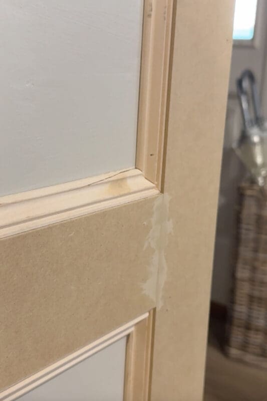 Applying wood filler over a brad nail hole on box molding wall trim to hide the nail spot before sanding, priming, and painting.
