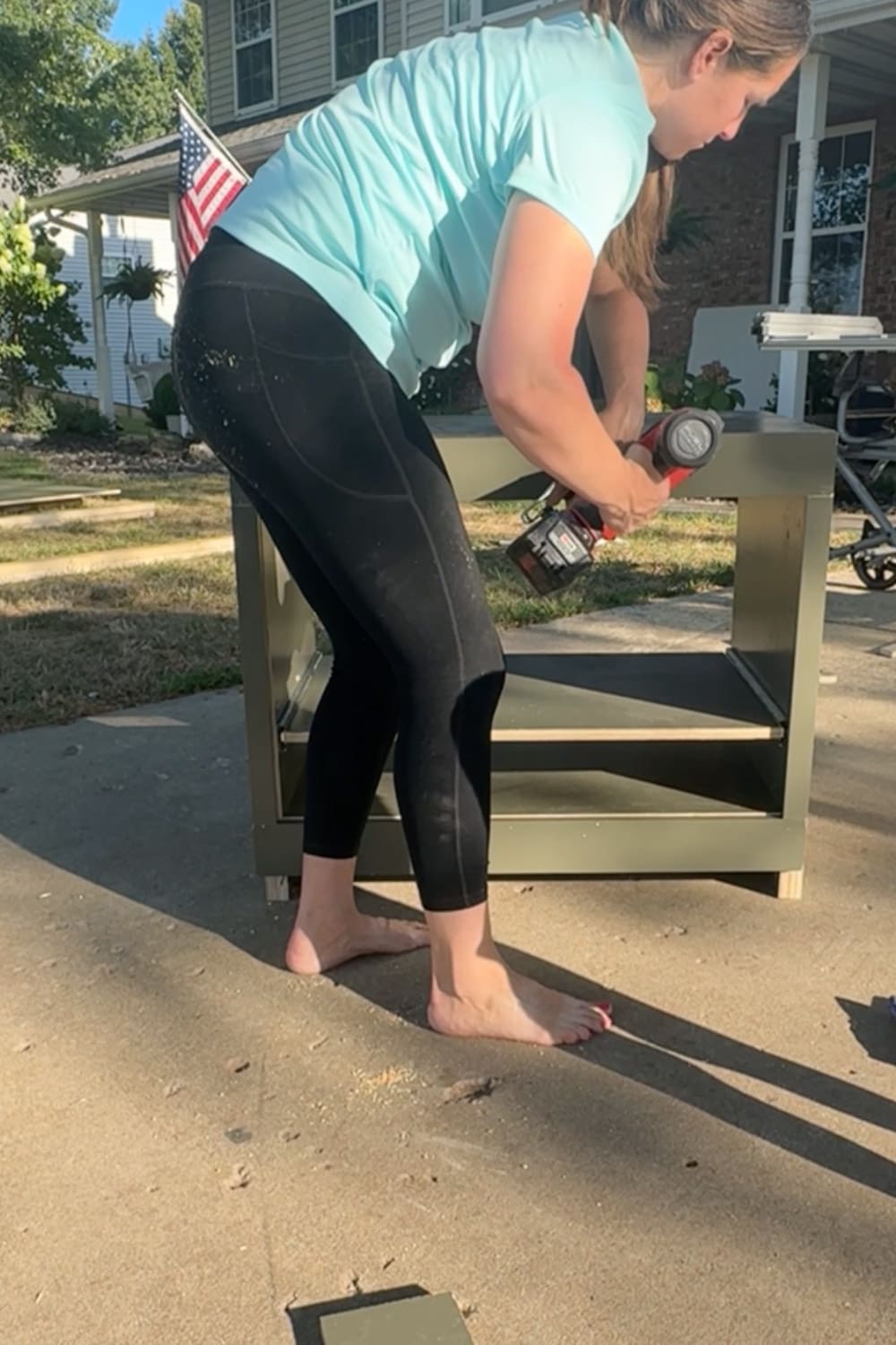 Attaching a painted cabinet face frame to the front of a base cabinet using a brad nailer after applying wood glue.