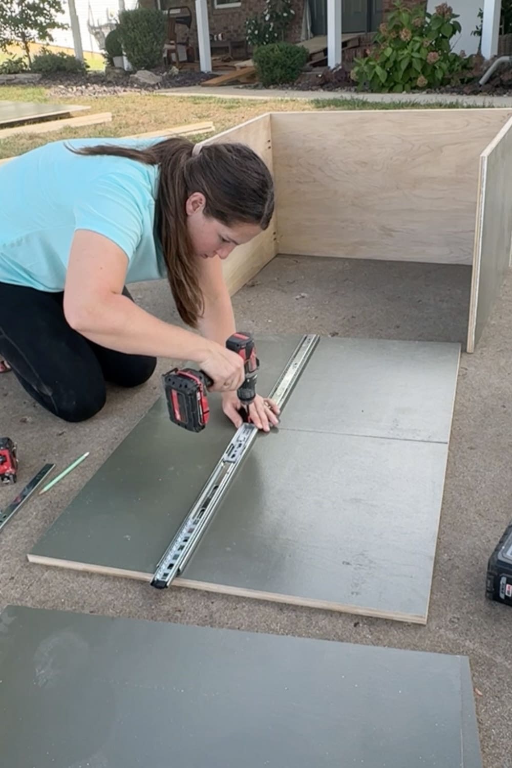 Attaching metal drawer slides to painted plywood cabinet sides with a drill, building the base cabinet for our DIY built-in bookshelves and home library wall.