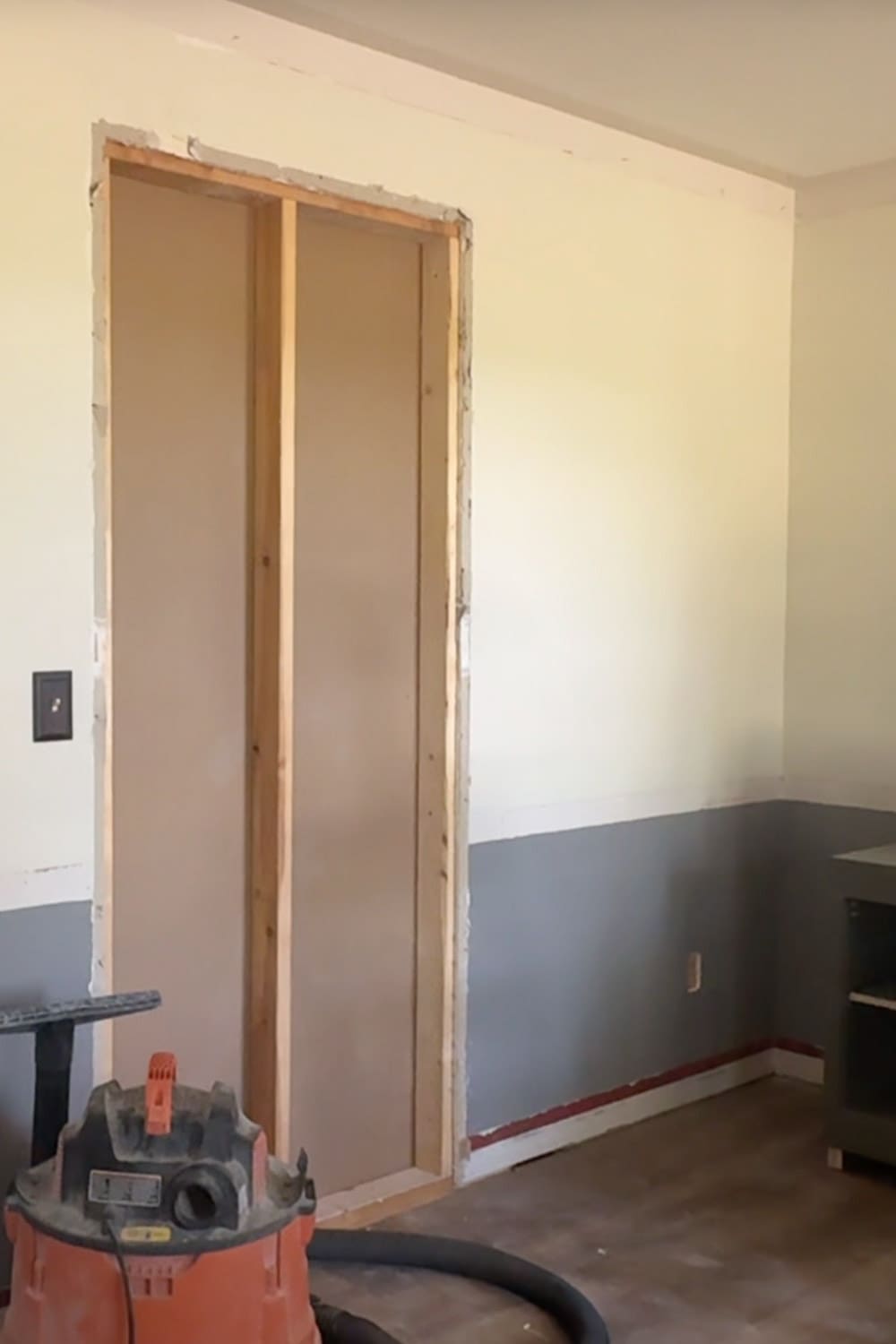 Drywall patch closing off the old kitchen opening to create a full wall for built-in bookshelves in a home library remodel.