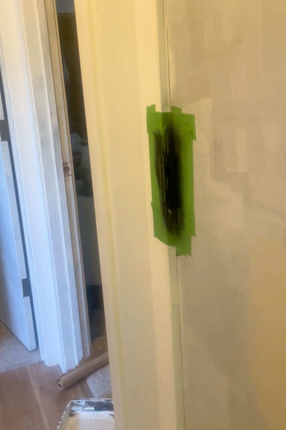 reshly spray painted black door hinge with tape masking on door frame