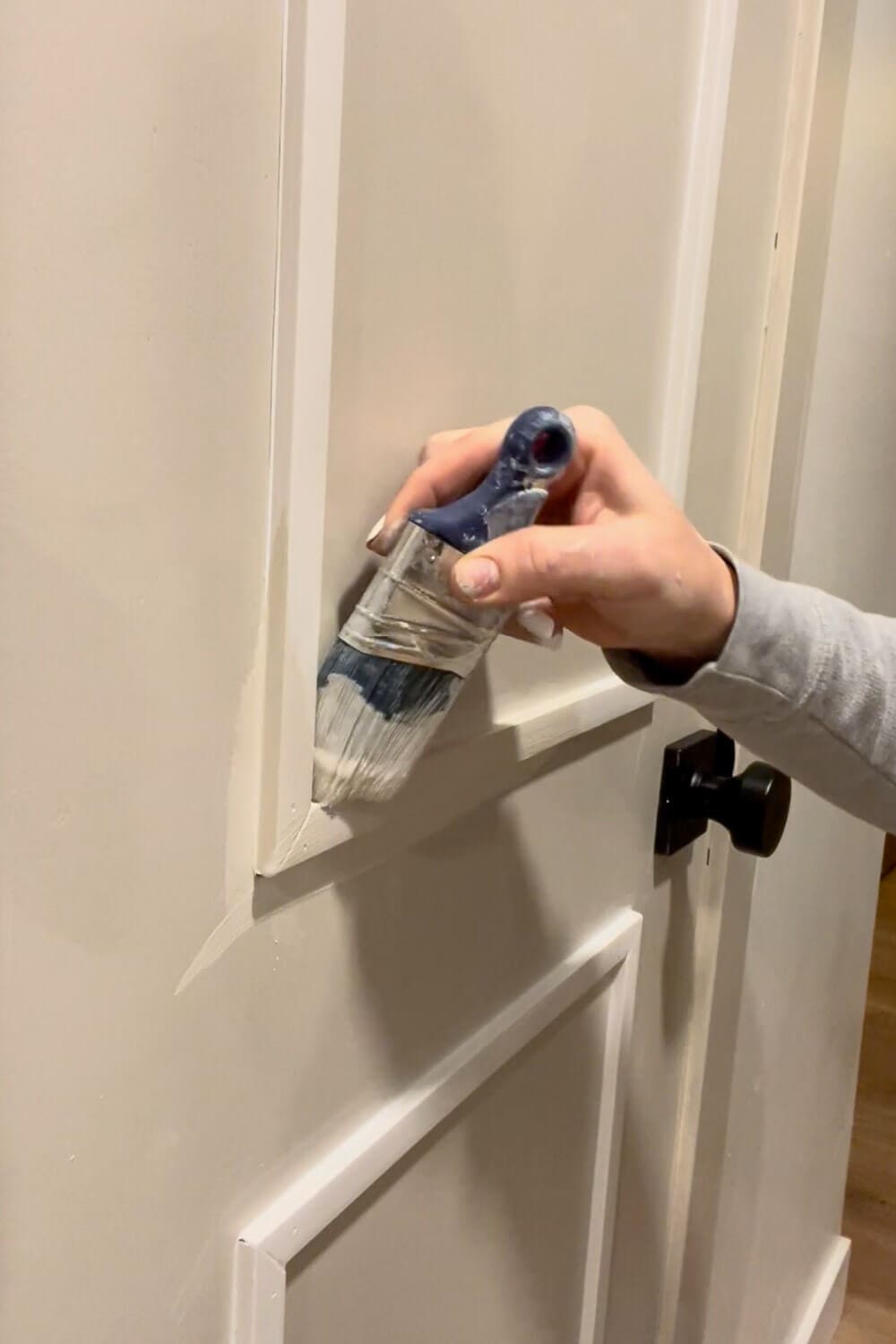 Painting door trim edges with small paintbrush for interior door makeover