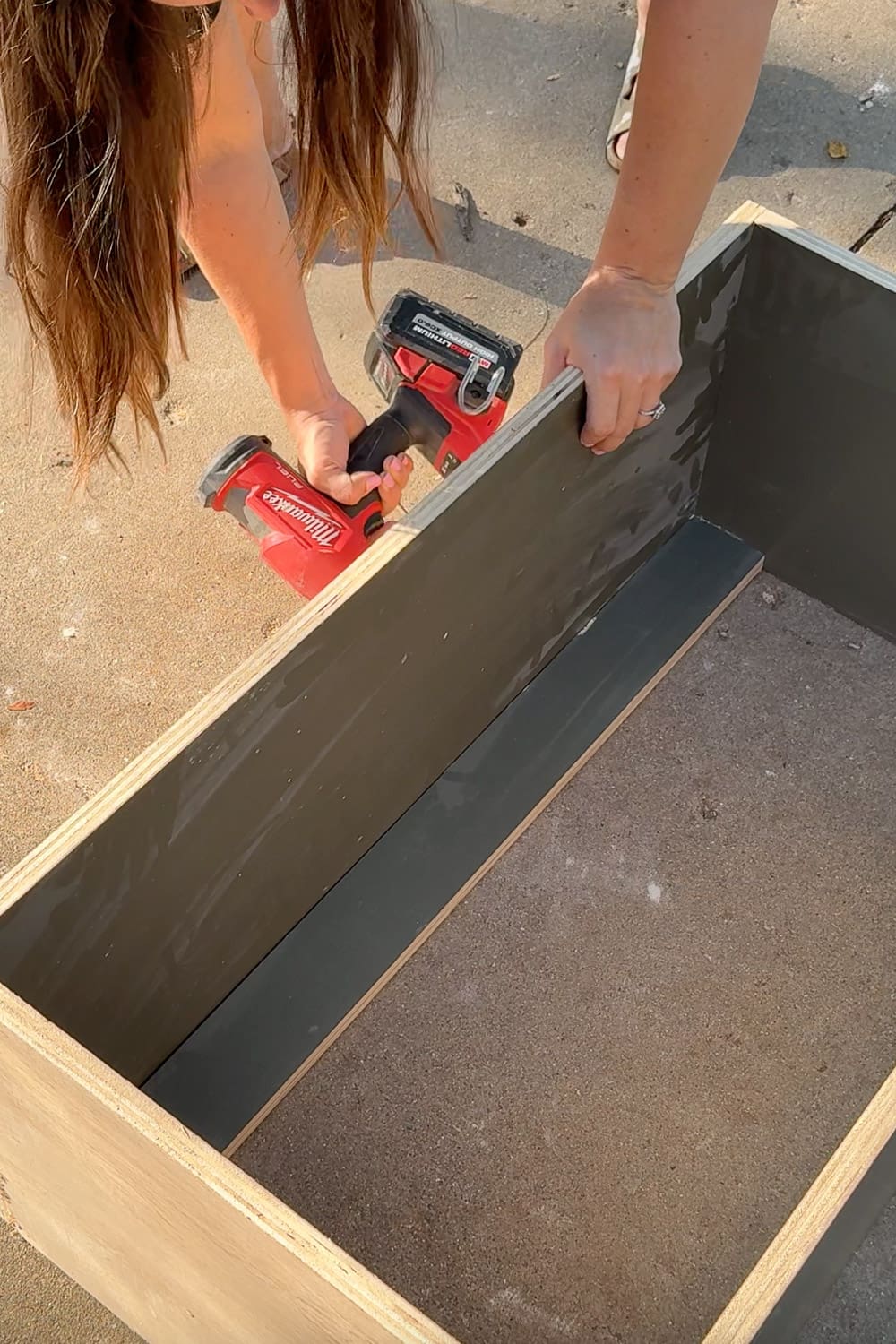 Securing the top stretcher to the bookshelf with a drill/driver while building custom DIY bookshelves for a home library.