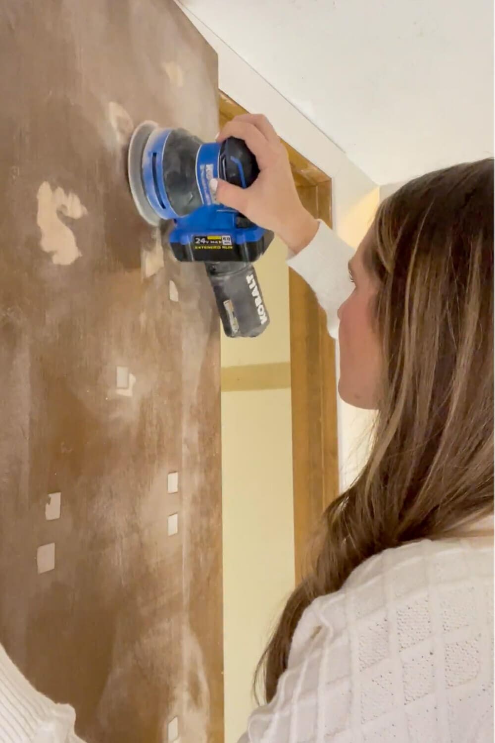 Sanding adhesive residue off interior door with electric sander