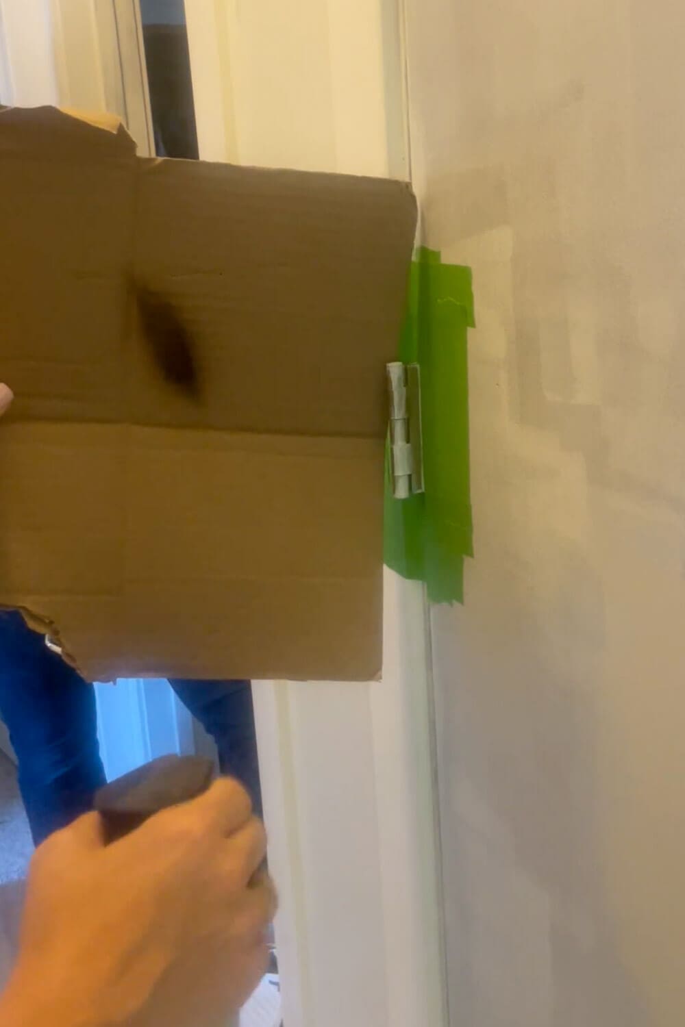 Cardboard paint shield protecting door frame while spray painting hinge black