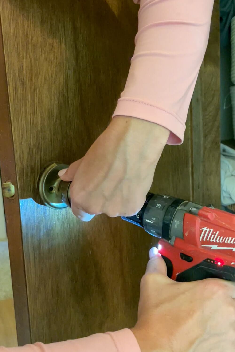 Removing old doorknob with Milwaukee drill before interior door upgrade