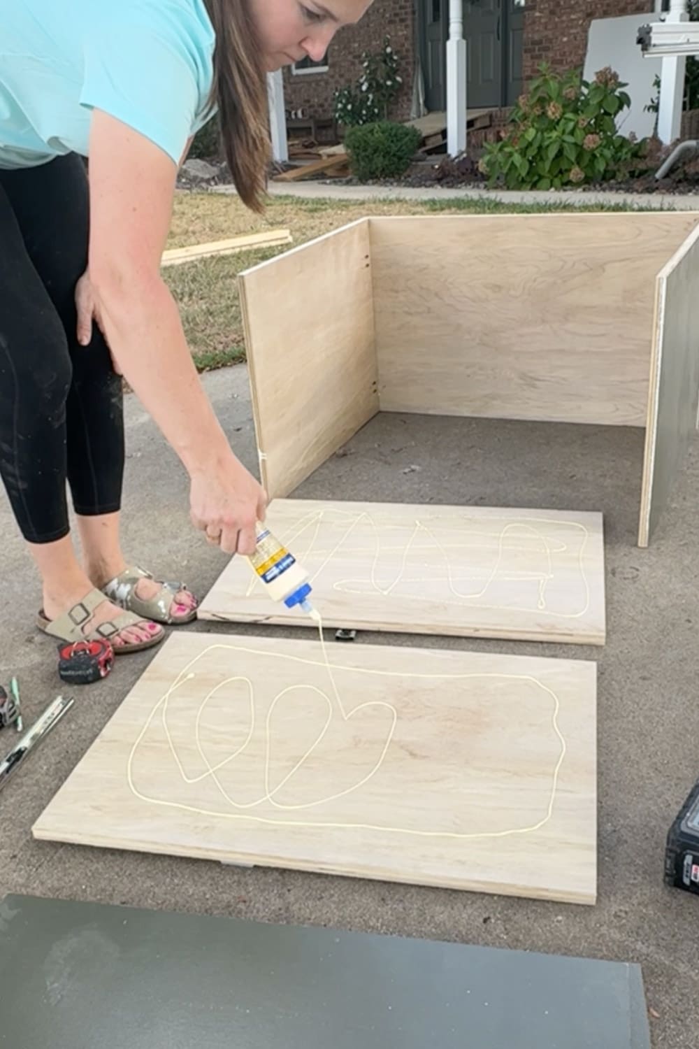 Applying wood glue to plywood panels before assembling a drawer box for the base cabinet in our DIY built-in bookshelves and cozy home library.