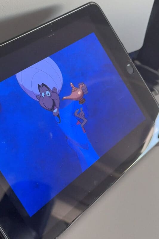 Kids watching Aladdin genie scene on tablet as inspiration for how to surprise kids with a Disney trip using a genie lamp