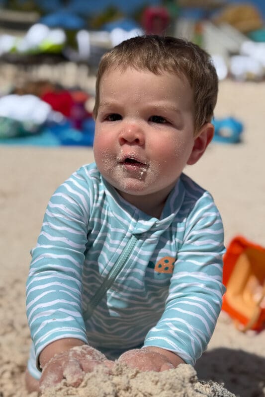 baby with sandy face playing on beach at lookout cay lighthouse point during family beach day