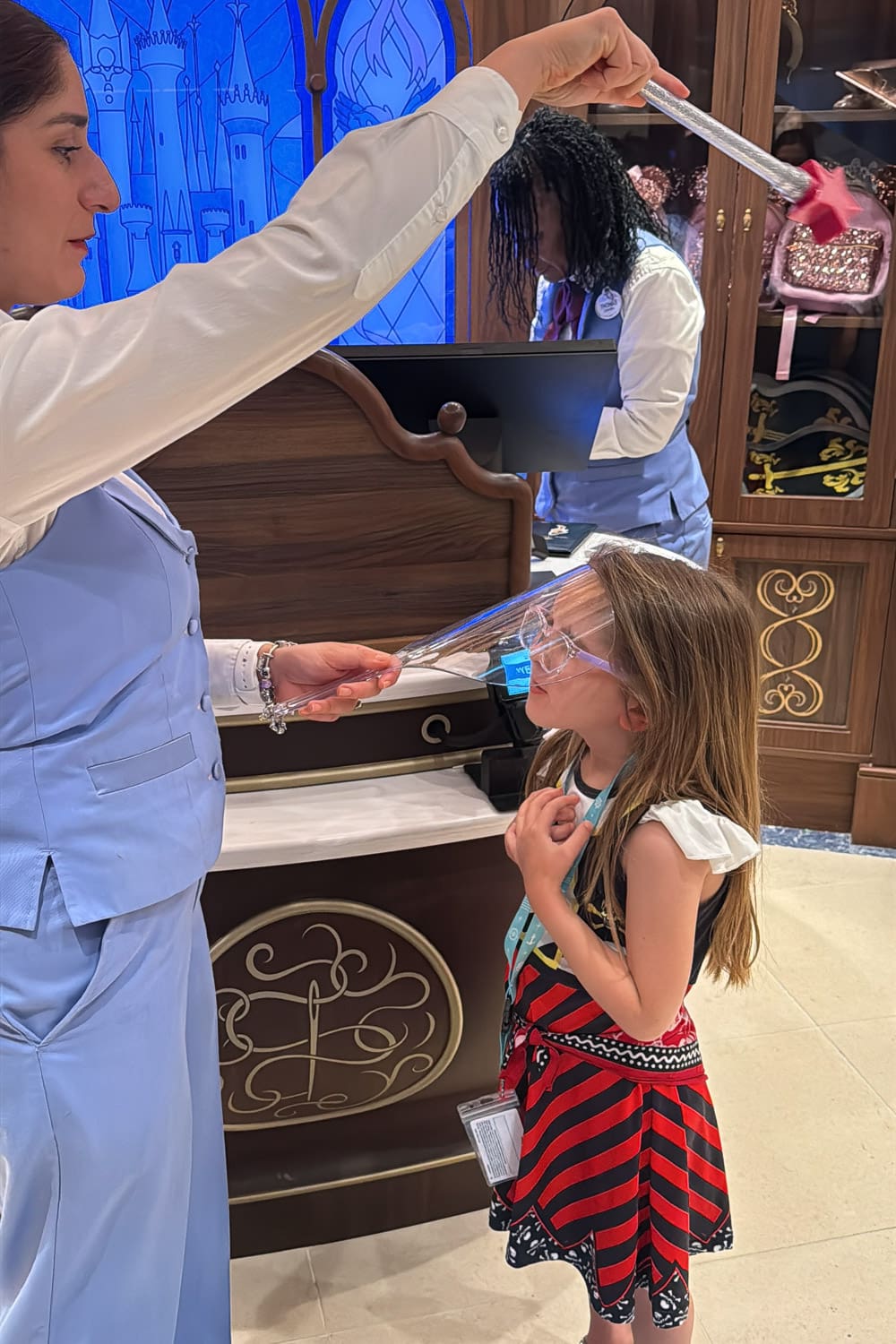 cast member sprinkling pixie dust on young girl at bibbidi bobbidi boutique during magical kids experience
