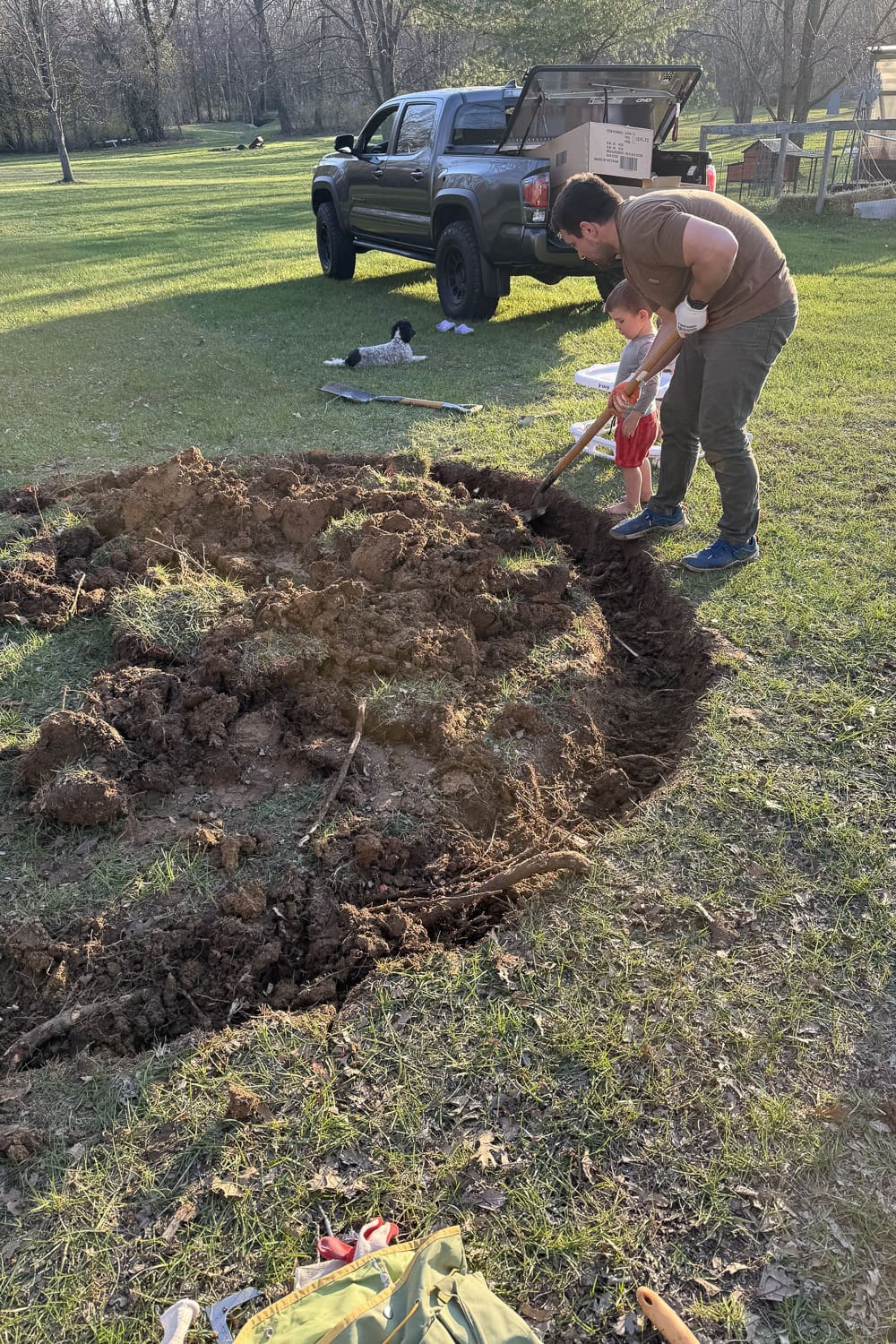 Digging the outline of an in-ground trampoline pit by hand using a shovel along the marked circle in the backyard