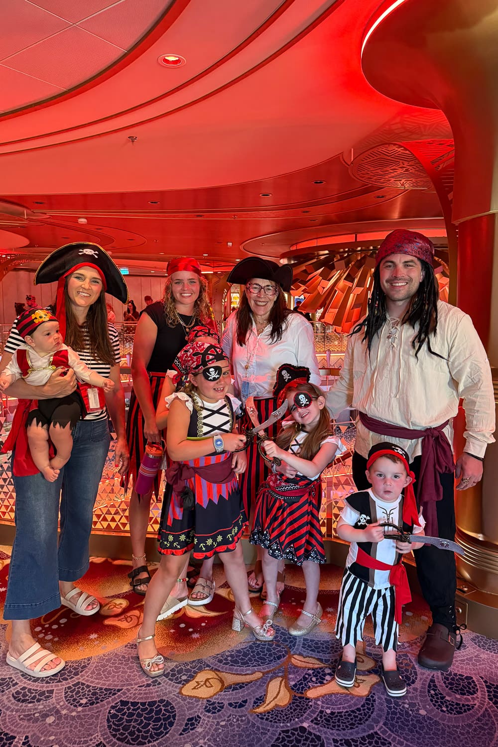 family dressed in pirate costumes on disney cruise ship during pirate night with kids wearing themed outfits and holding toy swords