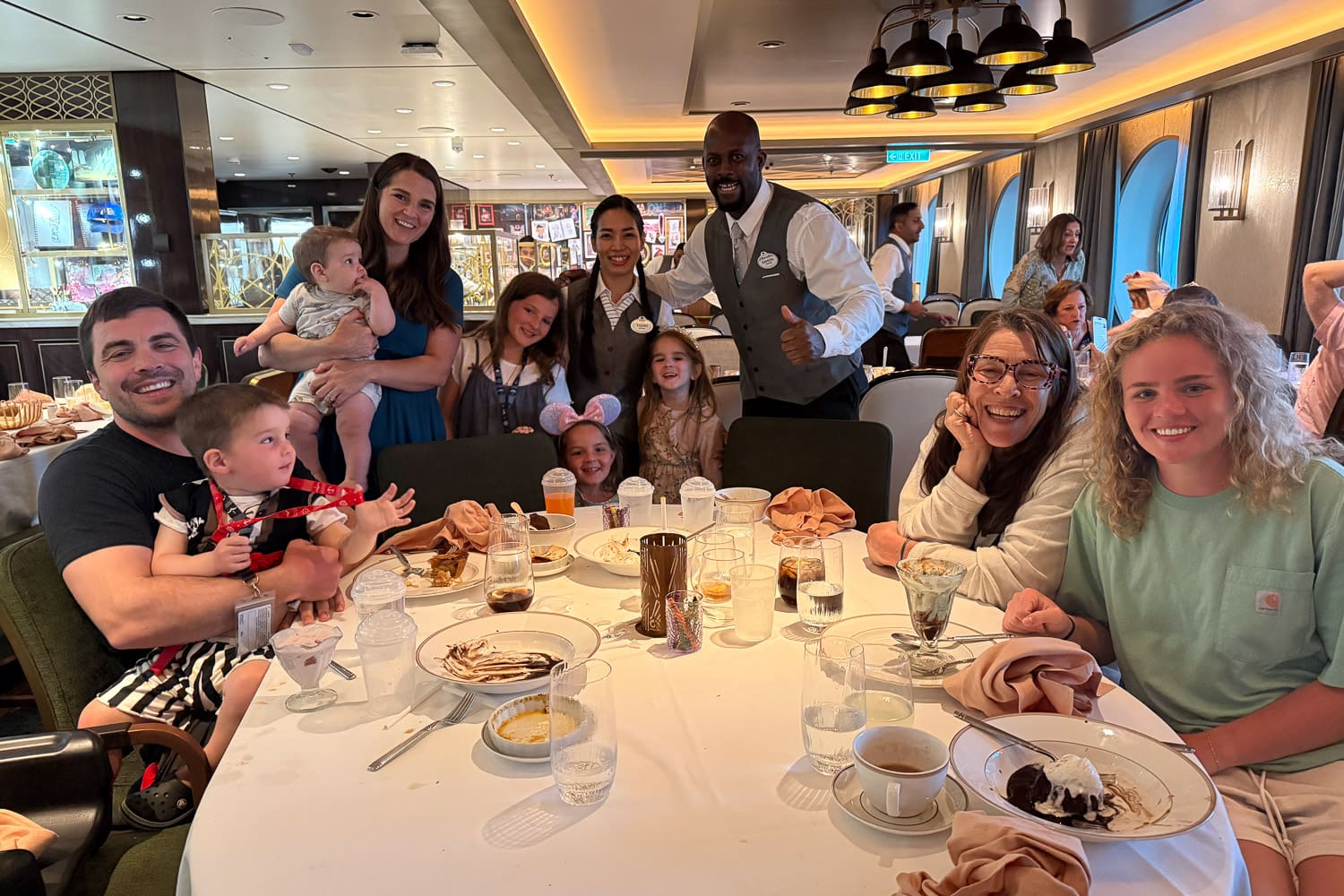 large family with kids dining together on the Destiny ship during rotational dining with servers and themed restaurant interior
