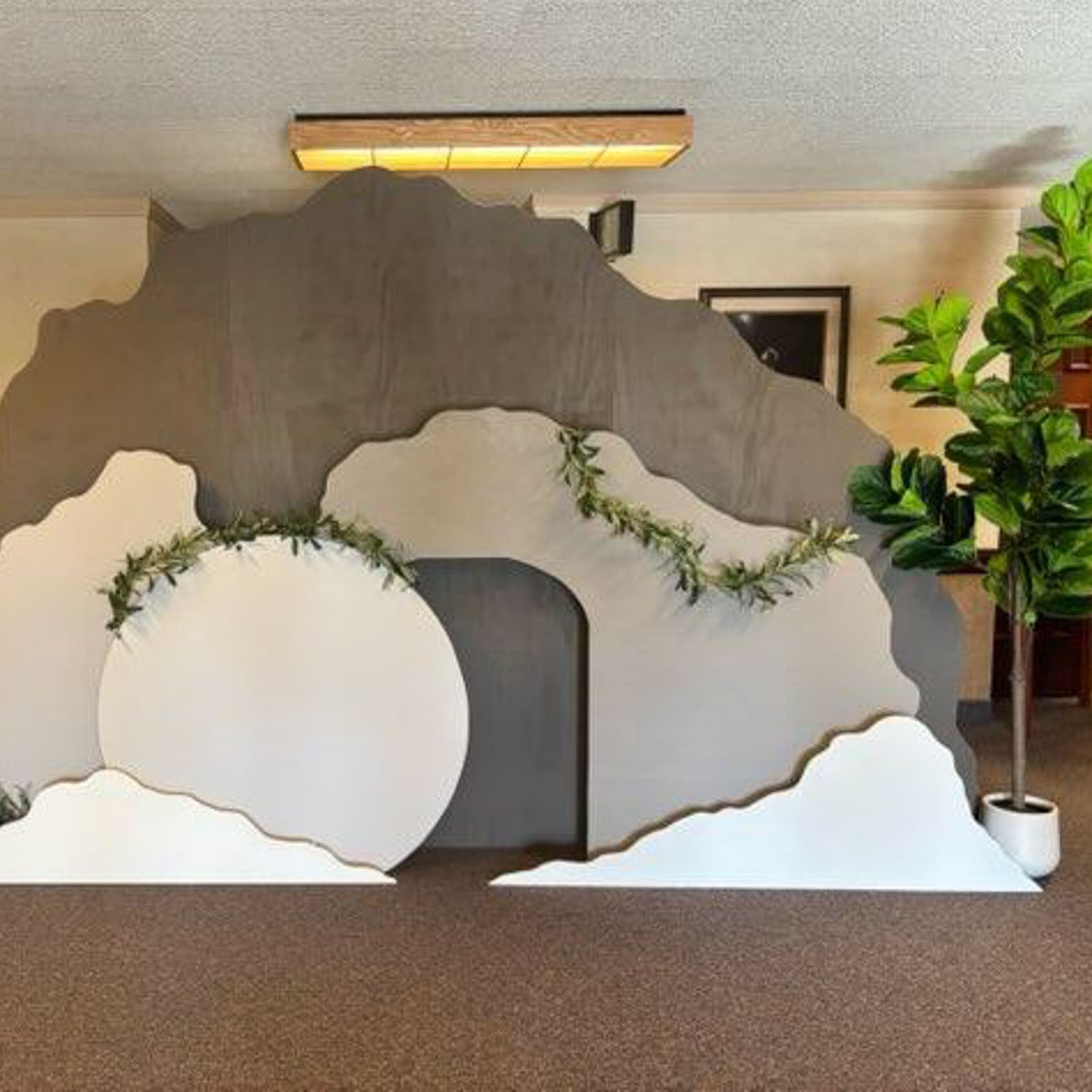 DIY empty tomb display for an Easter church activity for kids, featuring a large stone rolled away and greenery to represent the resurrection of Jesus Christ