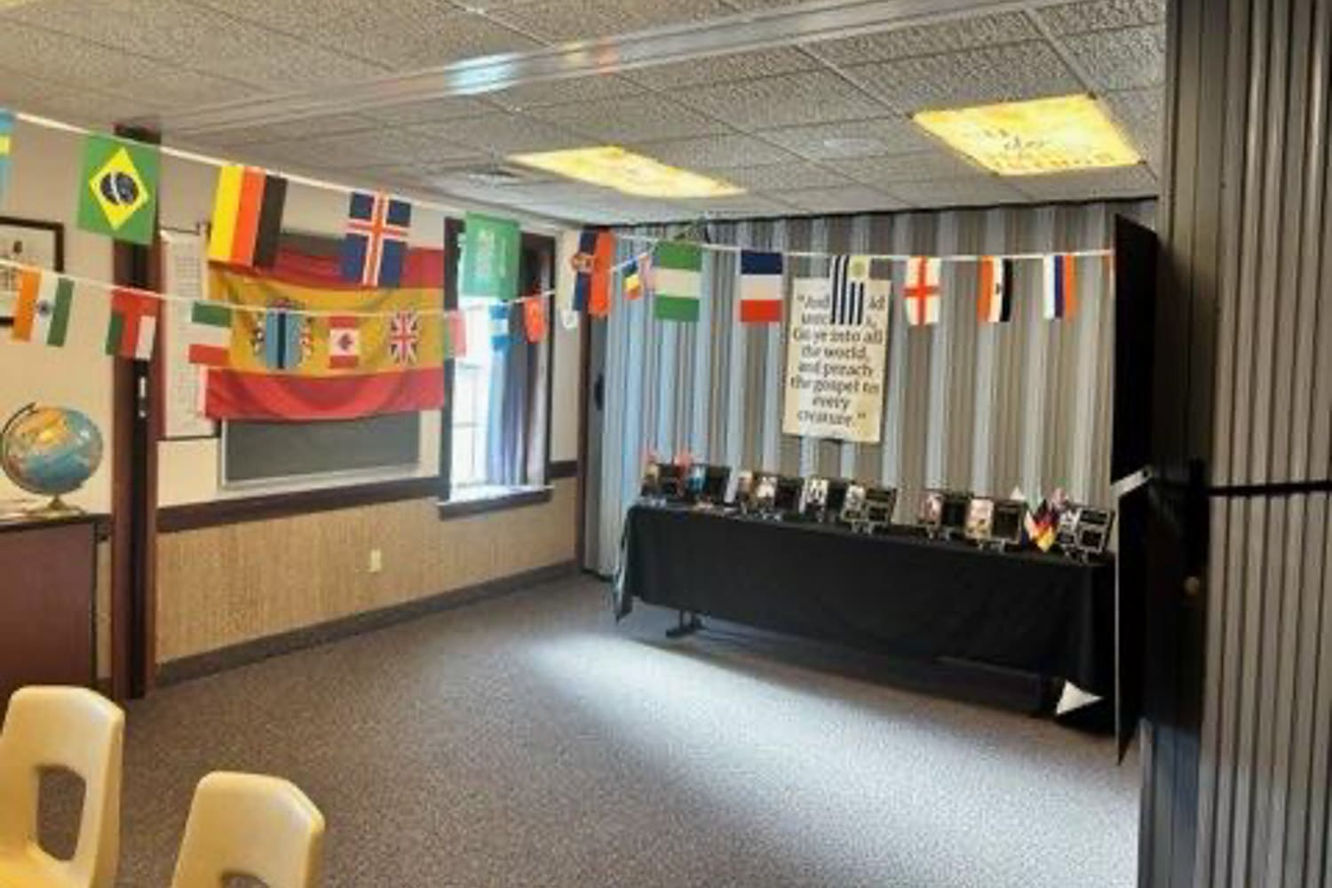 Go and Tell station for an Easter church activity for kids featuring international flags, missionary display table, and global theme for sharing the message of Jesus Christ