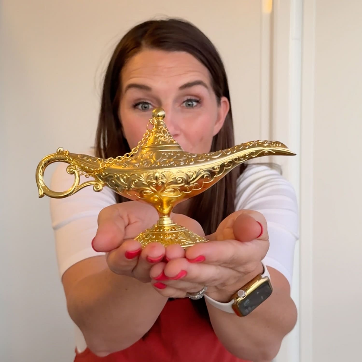 Holding a gold genie lamp used for a creative way to surprise kids with a Disney trip using a three wishes idea