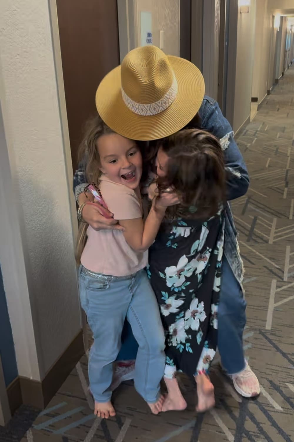 Kids hugging grandma in hotel hallway after surprise visit during Disney trip reveal