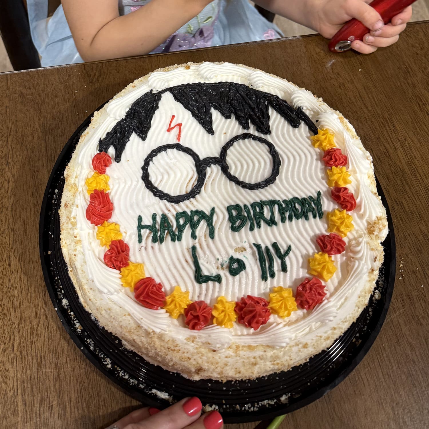 harry potter cake with glasses, lightning bolt scar, and black hair design with red and yellow frosting border for a birthday