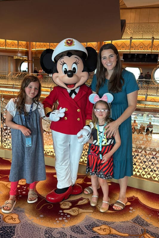 family with kids meeting minnie mouse dressed as captain on disney cruise ship during character meet and greet experience