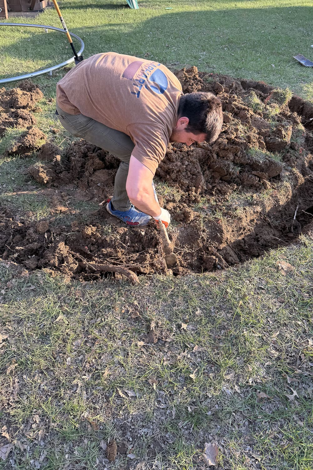 Close-up of digging the edge of a large hole and removing roots