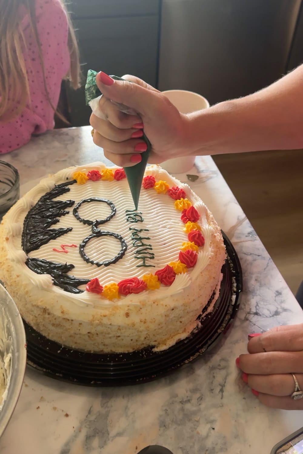 piping green frosting to write happy birthday message on harry potter cake